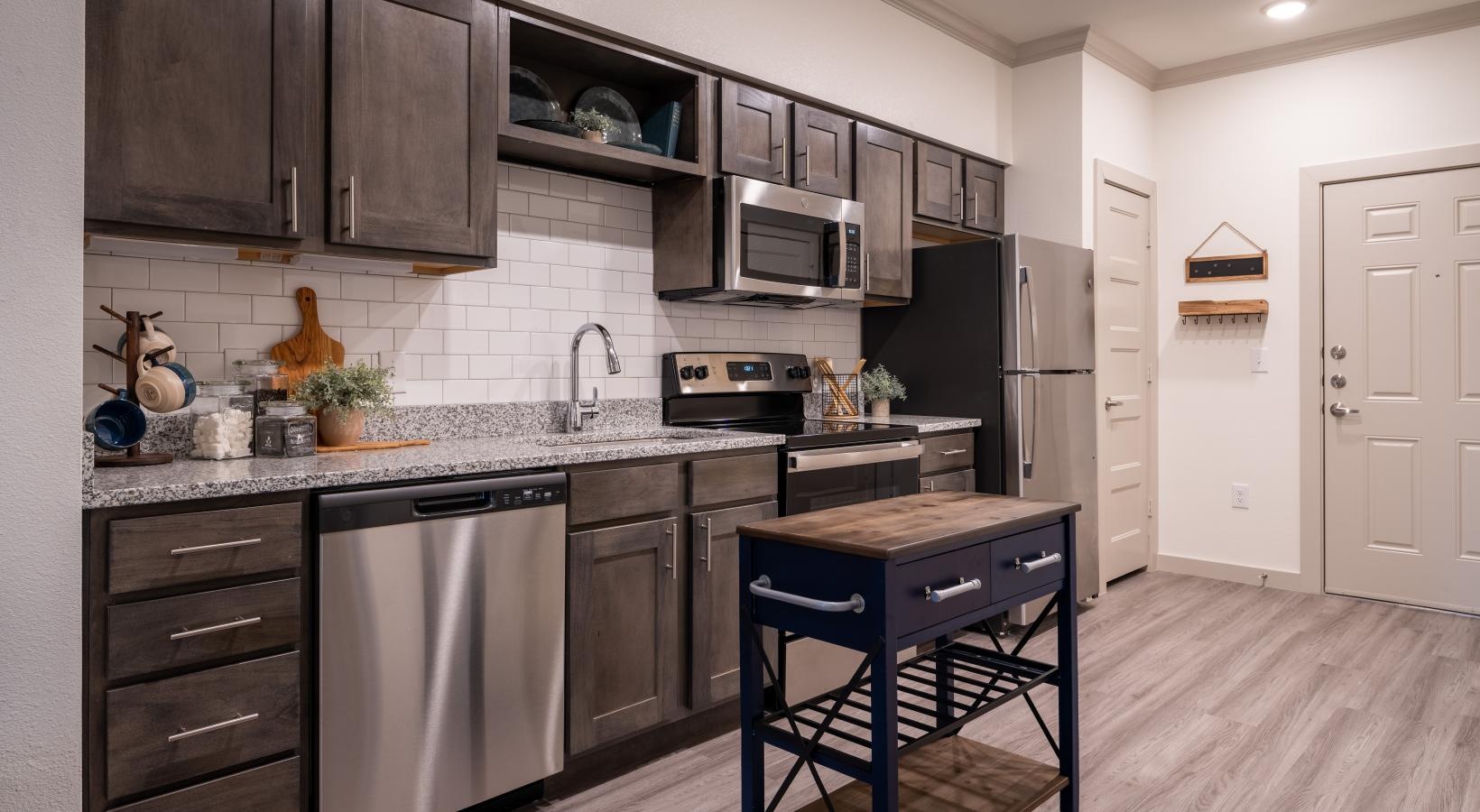 Settle into comfort at Preserve at Willow Park a kitchen with brown cabinets a dishwasher a sink a stove and a fridge