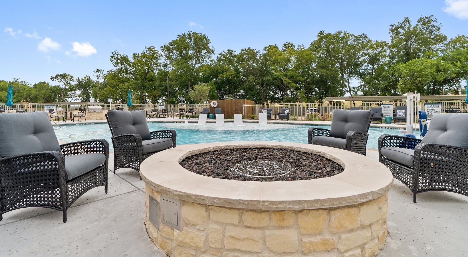 Relax and unwind poolside a group of chairs around a firepit in front of a pool