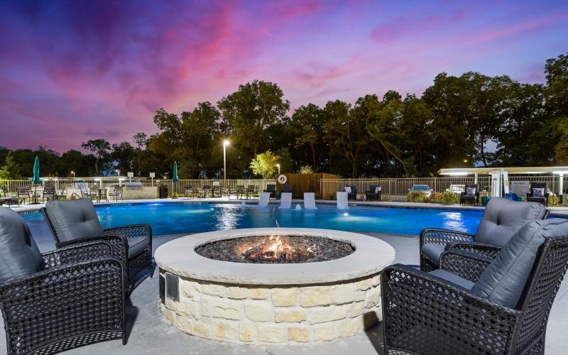 a pool with a fireplace and chairs around it