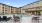 a pool with chairs and tables by it and buildings in the background